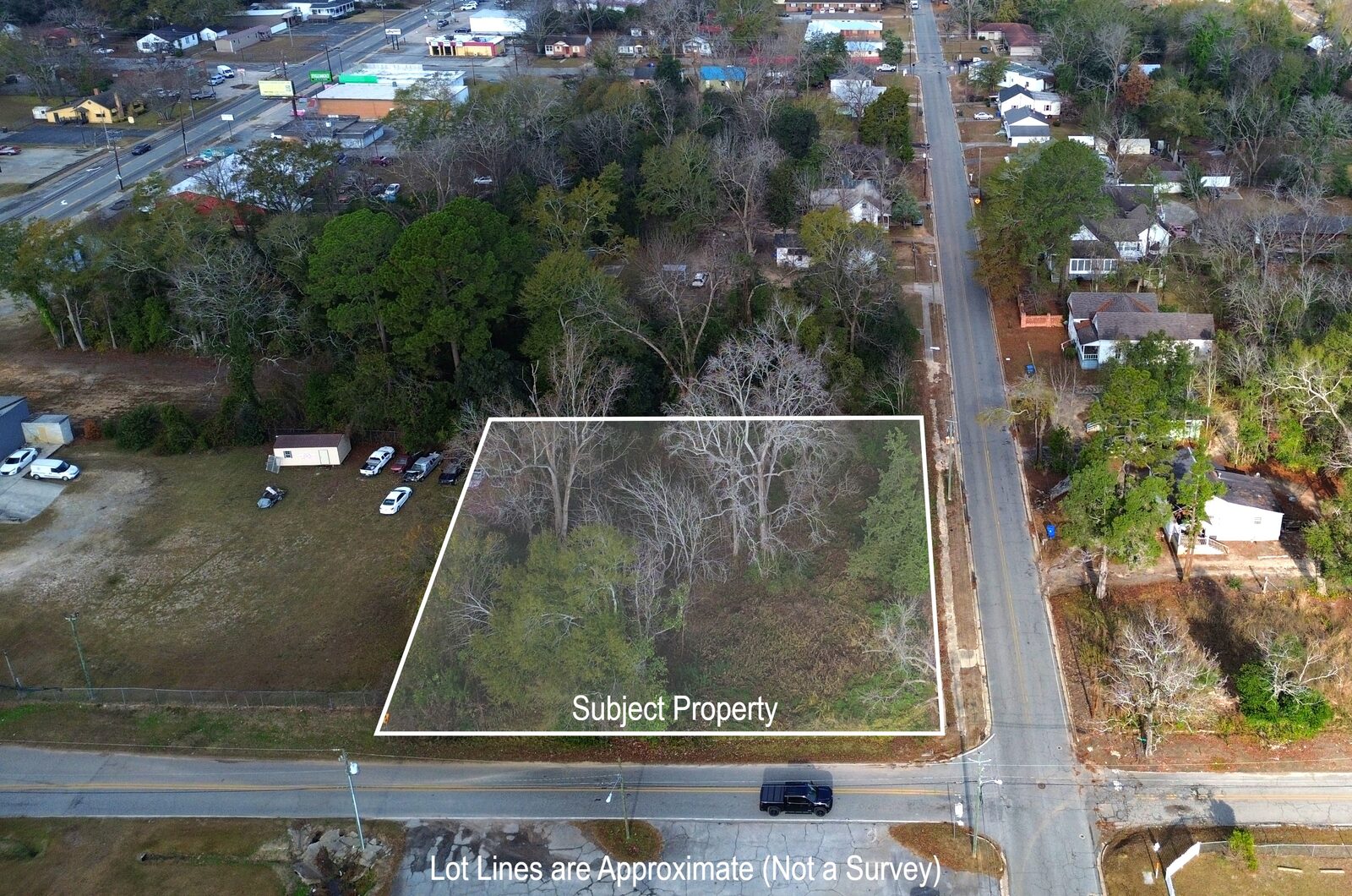 Aerial view of the corner lot outlined in white at the junction of N Franklin Street and E Moore Street, with commercial buildings adjacent.