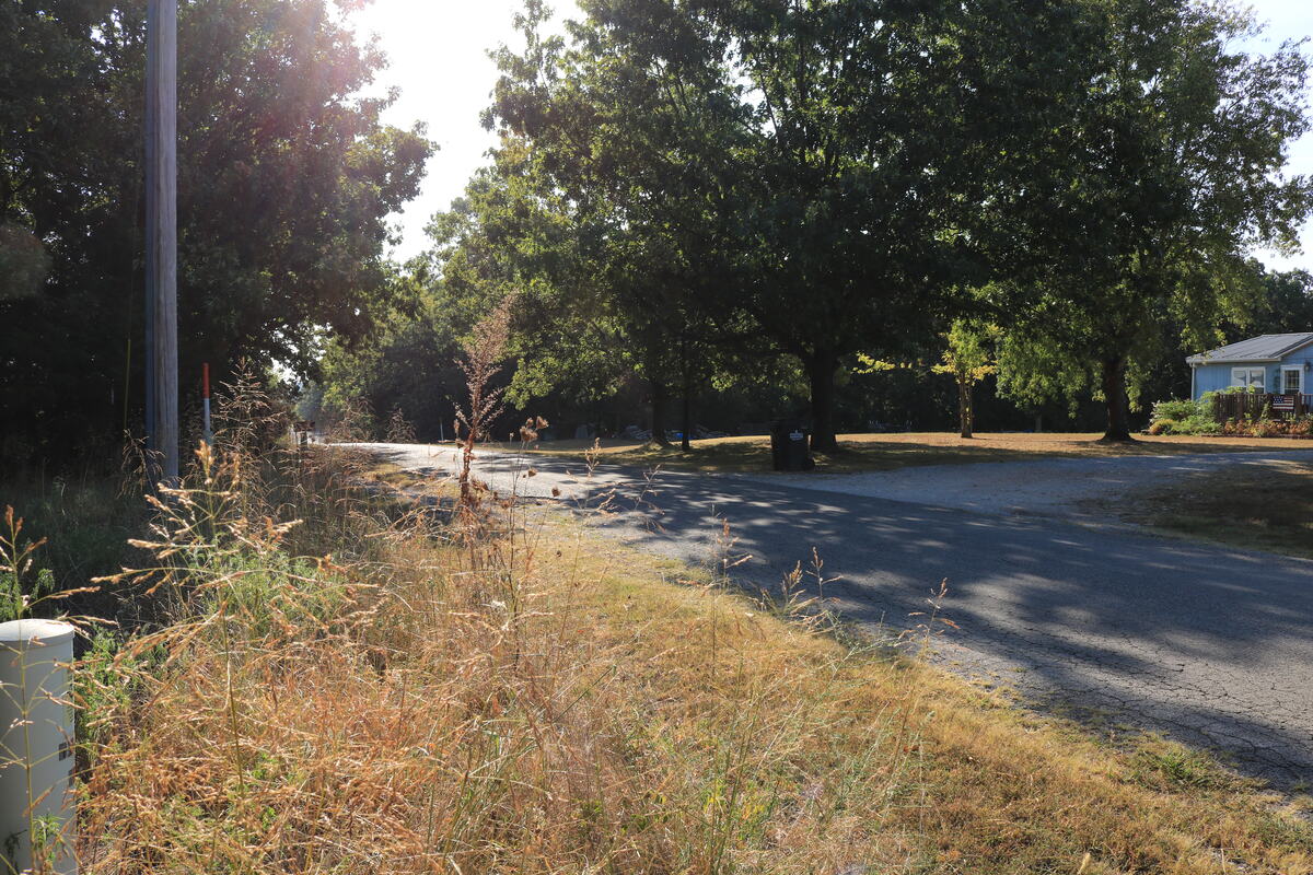View along the paved county road with a neighbouring house in the distance.