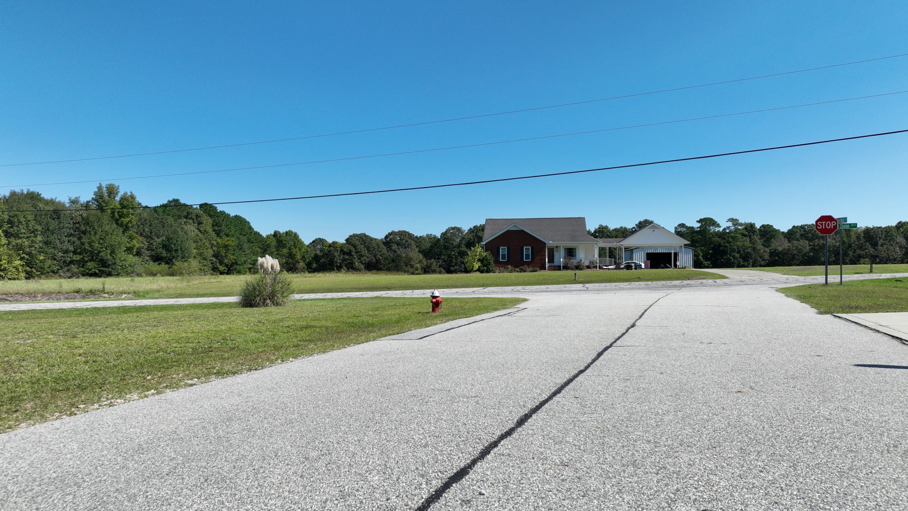 Ground view across Oxford Woods Drive toward the stop sign, a fire hydrant and the mowed lot.