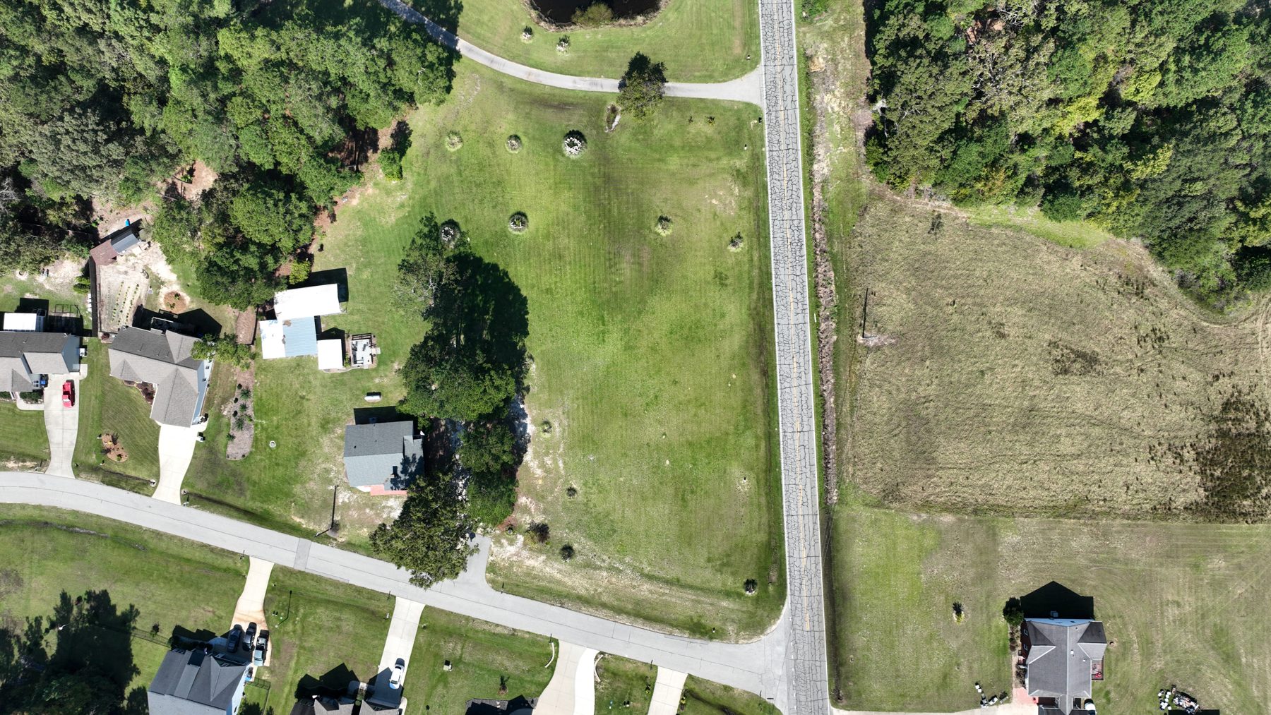 Drone view straight down on the mowed corner lots and the road.