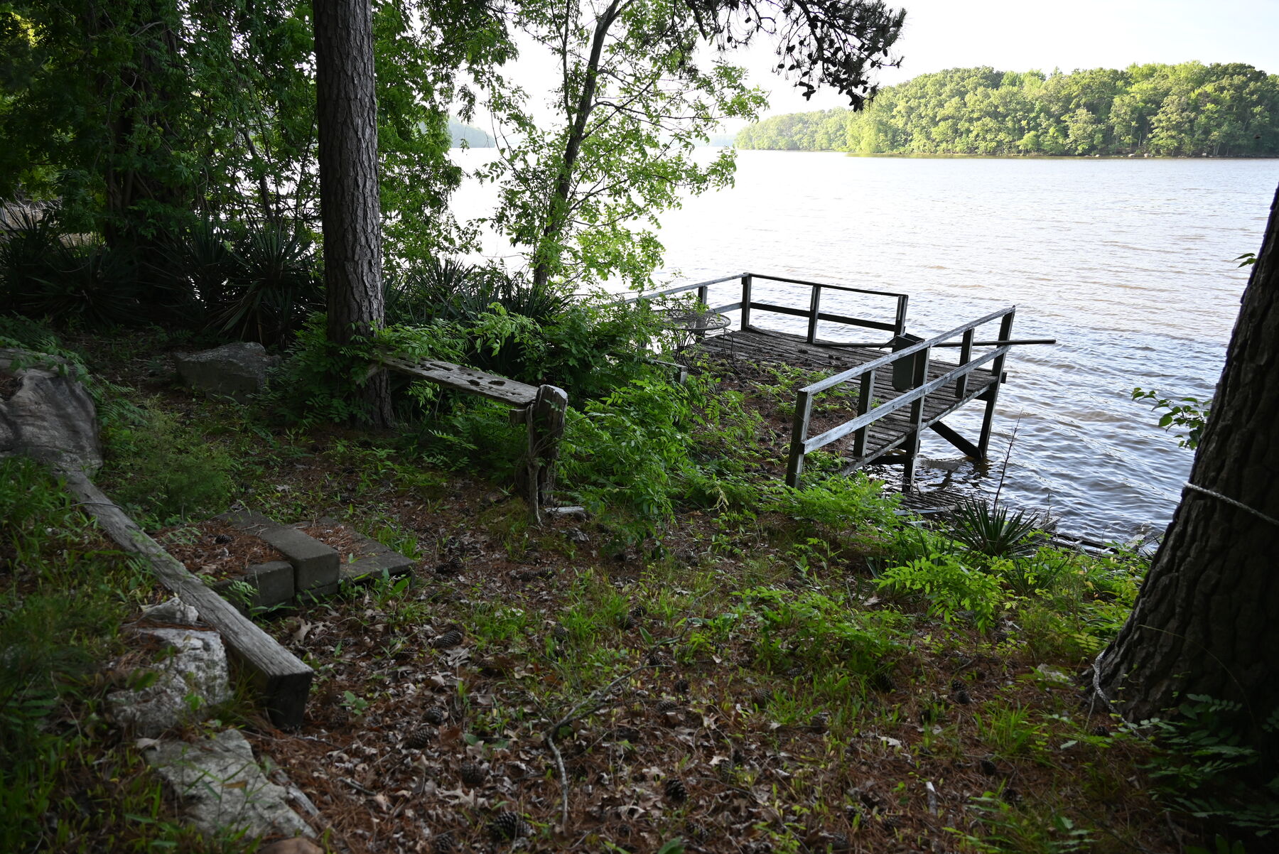 A wooden dock and steps down to the water, the lake and a wooded far shore beyond.