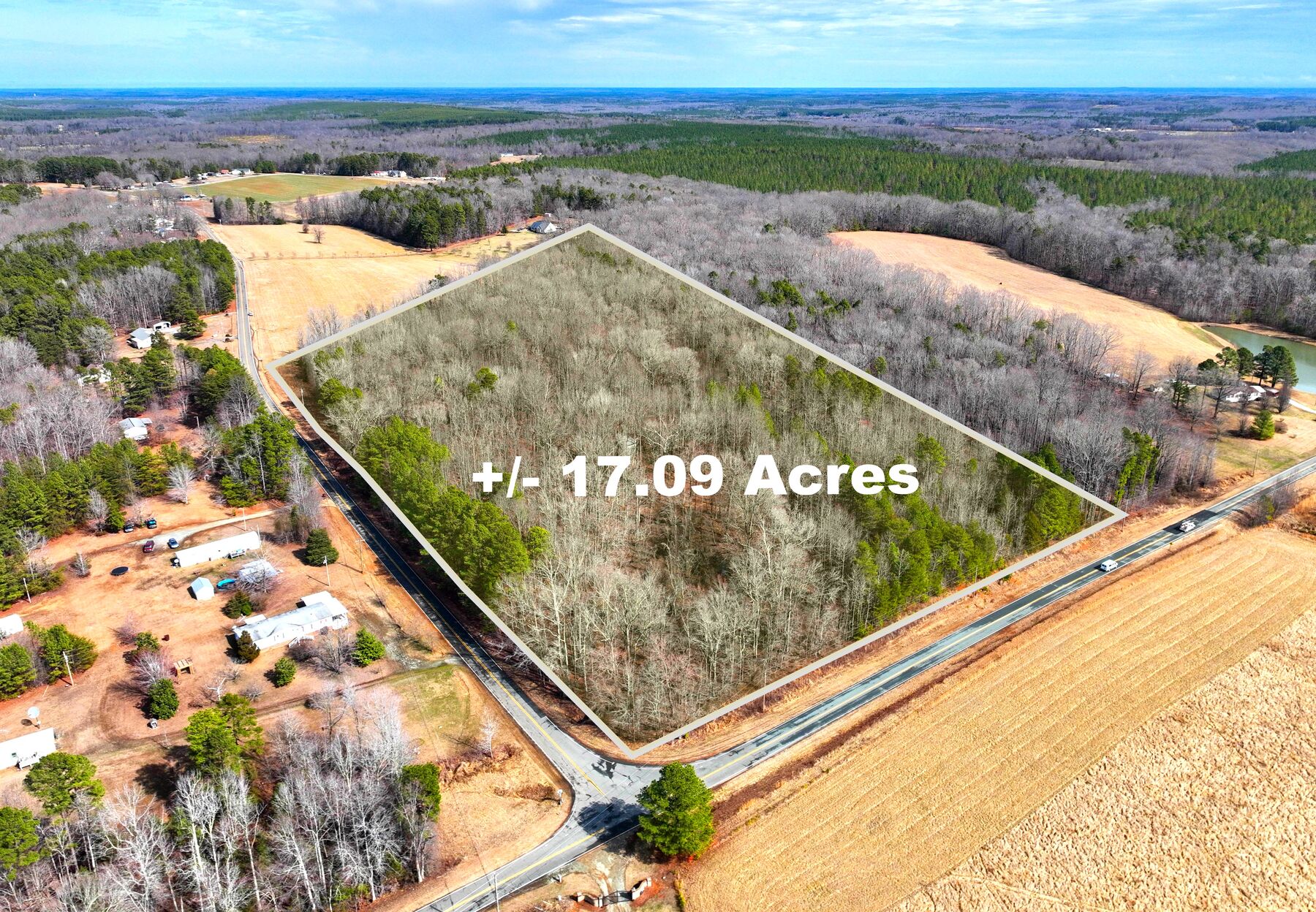 Aerial of the 17-acre wooded tract outlined in white at the corner of two paved roads, farm fields around it.